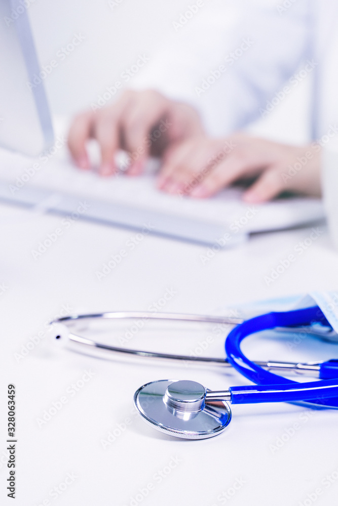 Business concept - Young female doctor woman working at office with computer, typing electronic medi