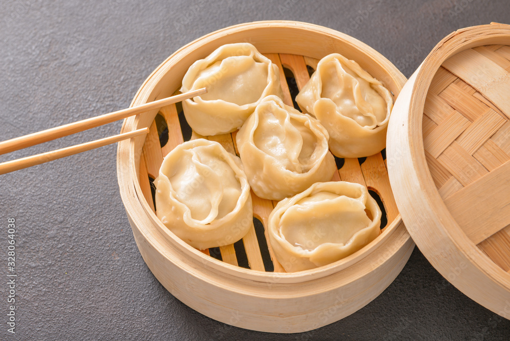 Steamer with oriental dumplings on dark background