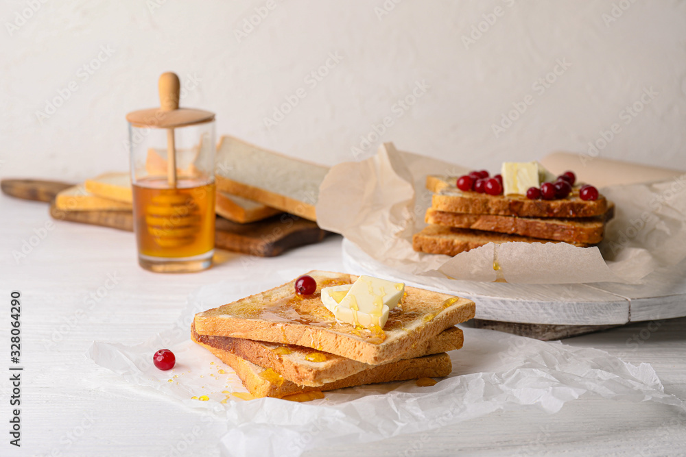 Tasty toasted bread with honey, butter and berries on table