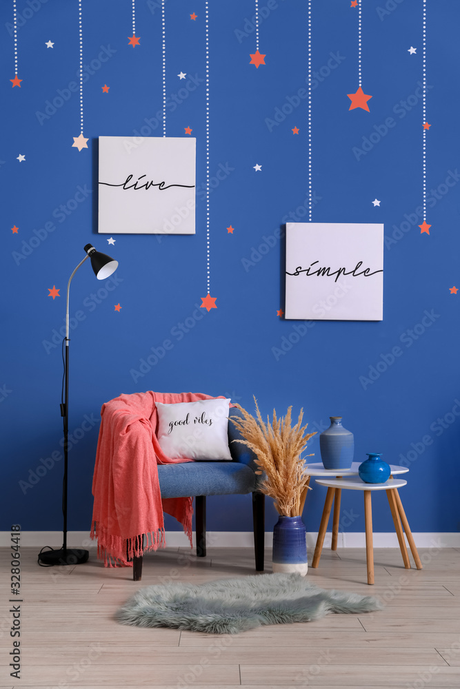 Stylish interior of room with armchair and table near blue wall