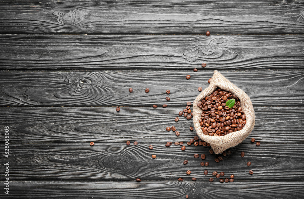 Bag with coffee beans on wooden background