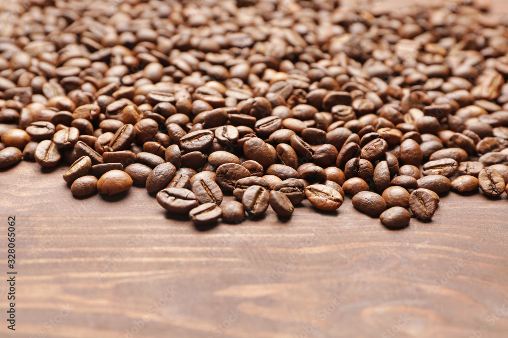 Many coffee beans on wooden background