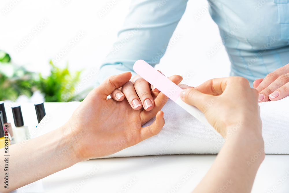 Manicurist using nail file and create clean shape