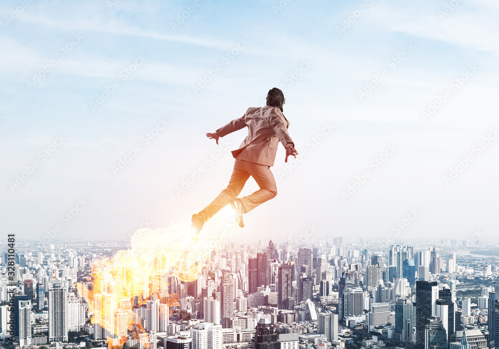 Businessman in suit and aviator hat flying in sky