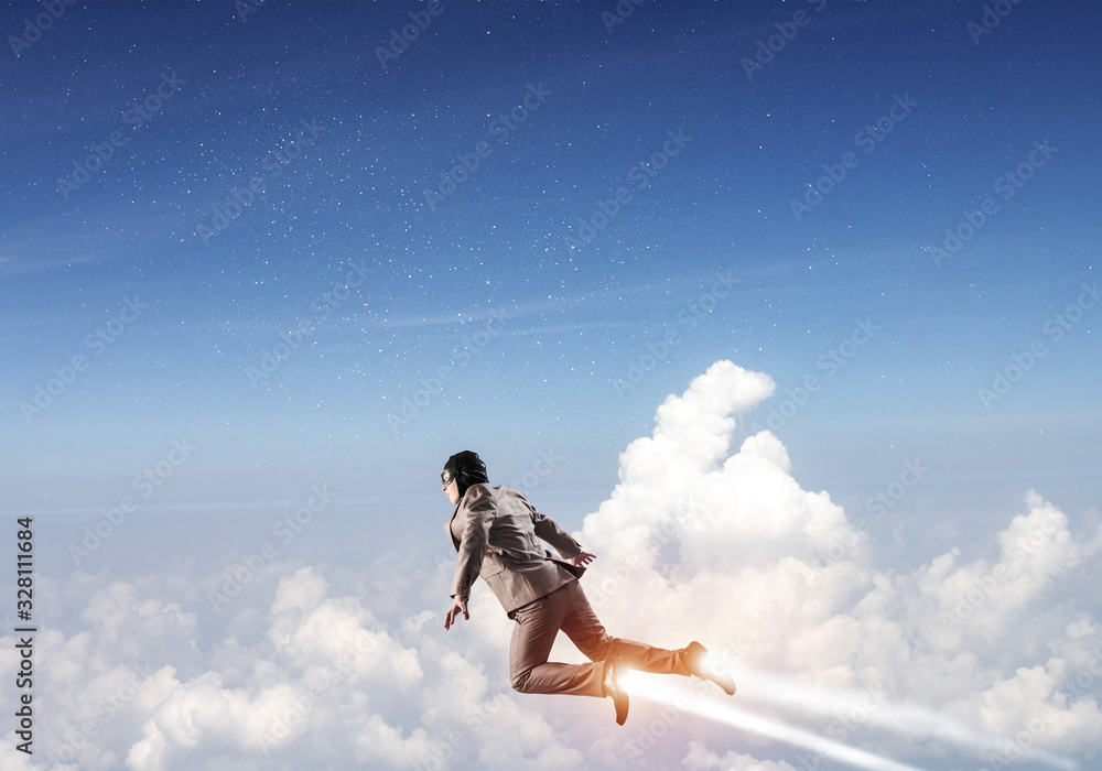 Businessman in suit and aviator hat flying in sky