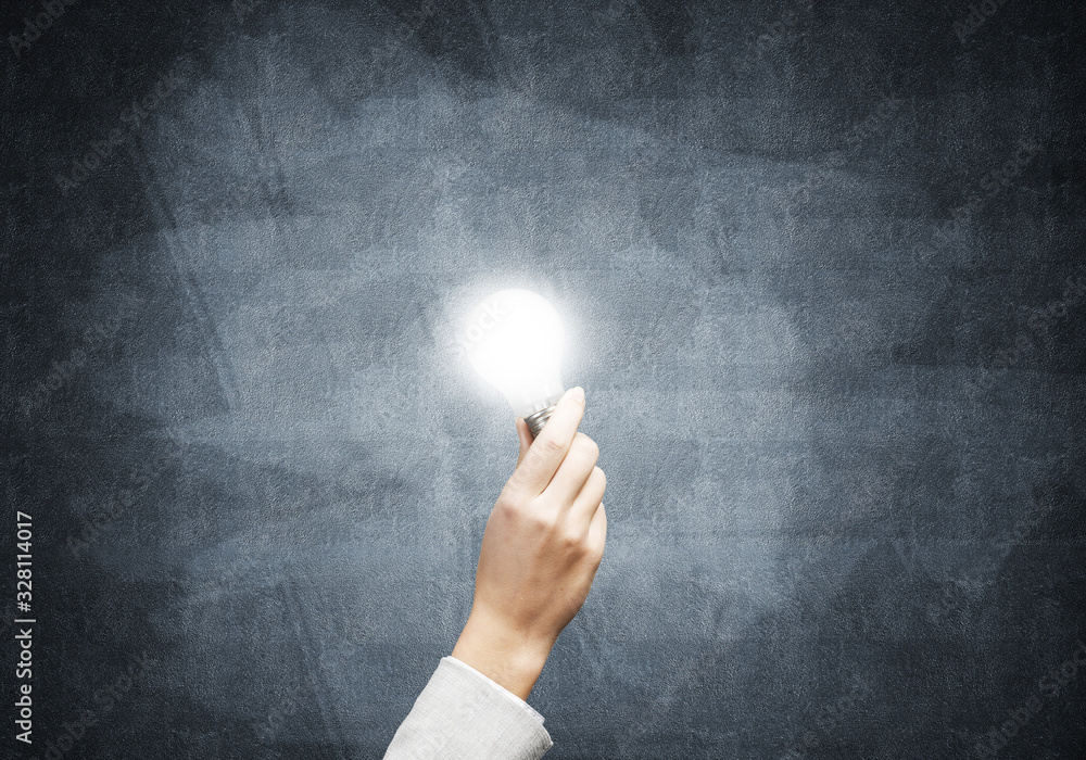 Businesswoman holding in hand glowing light bulb