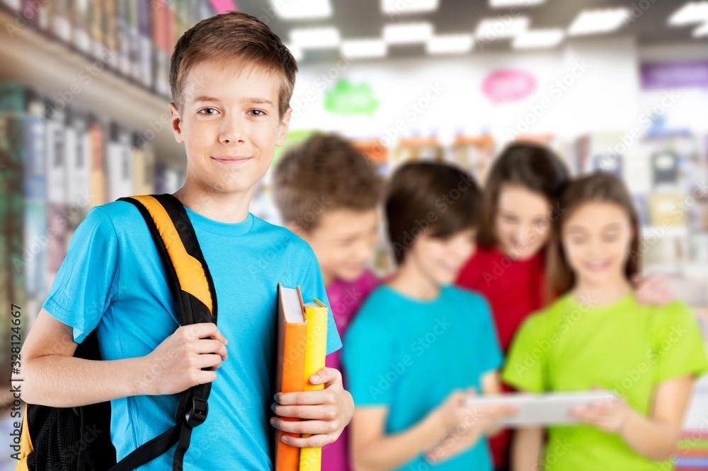 School boy with books and backpack on classmates background