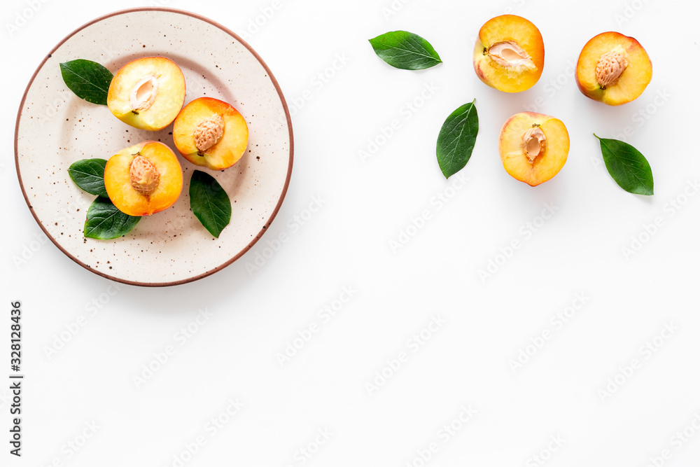 Peaches pattern with plate and leaves on white table top-down copy space