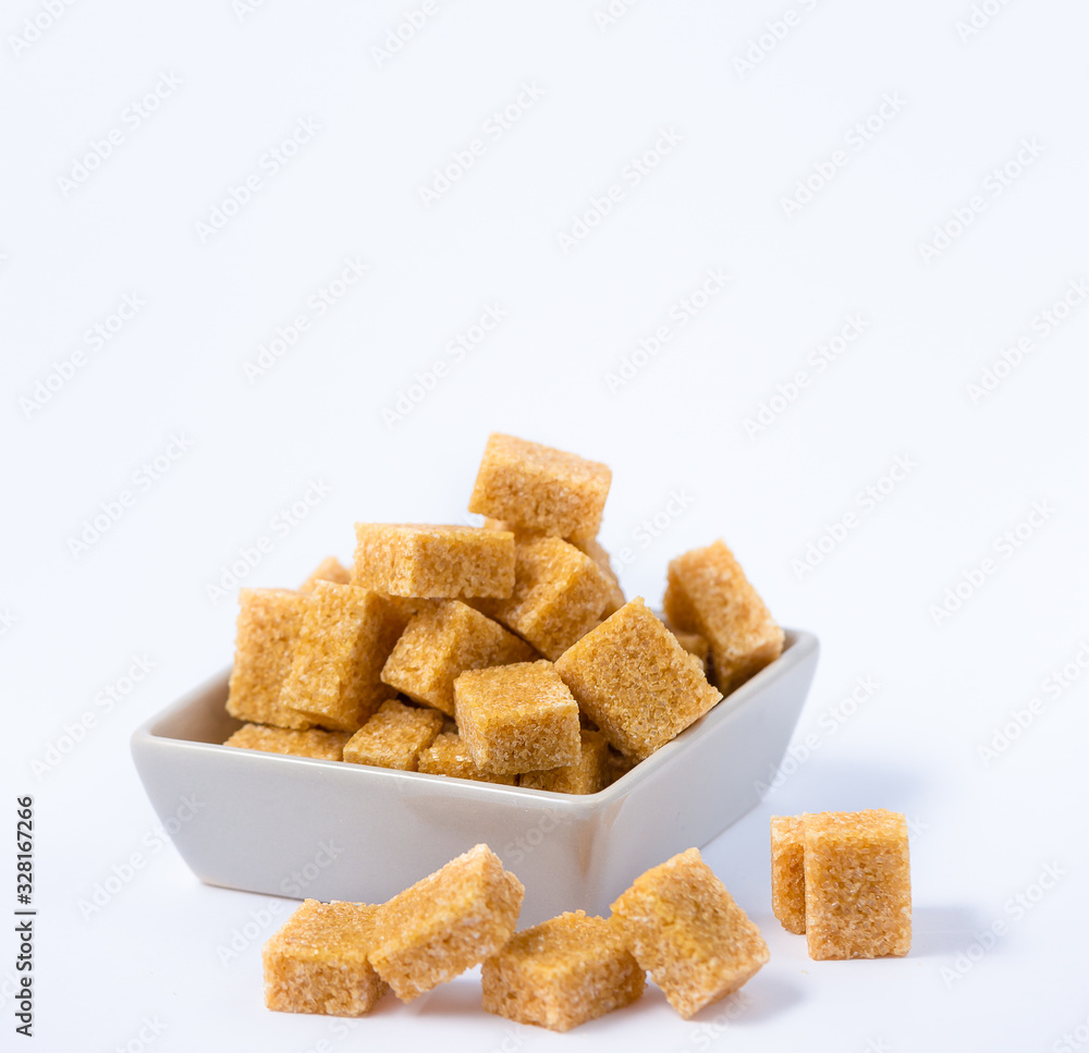 Brown sugar in a square cup on a white background, healthy sugar is used for cooking or desserts.