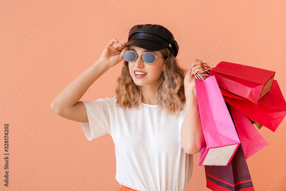 Beautiful young woman with shopping bags on color background