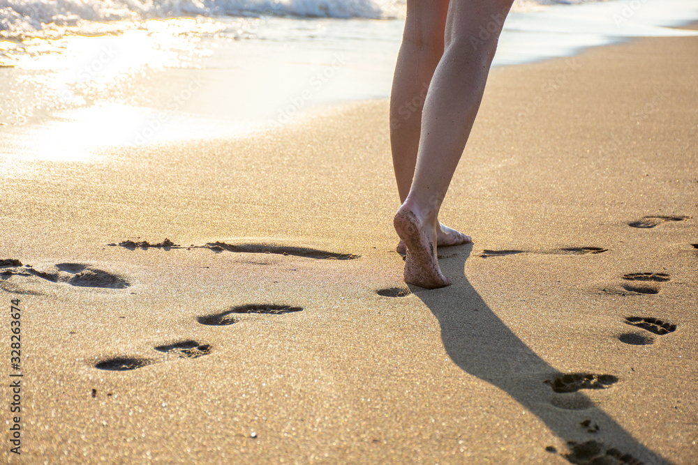 Woman walking on the beach at sunset