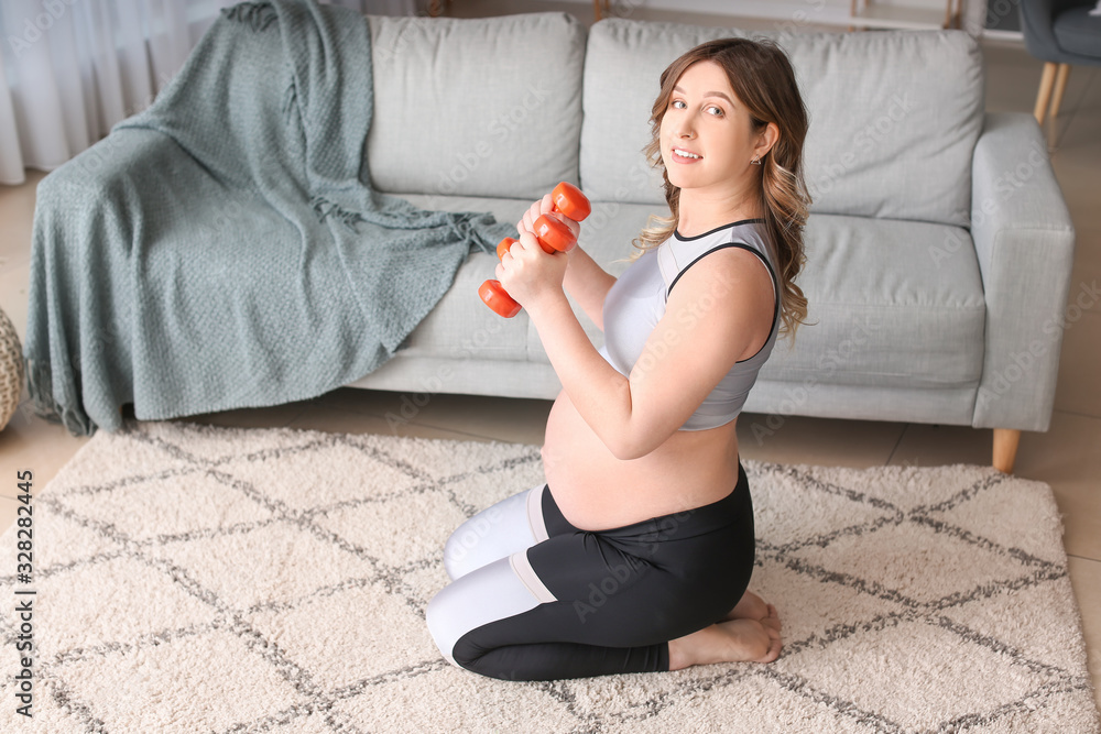 Sporty pregnant woman doing exercises at home