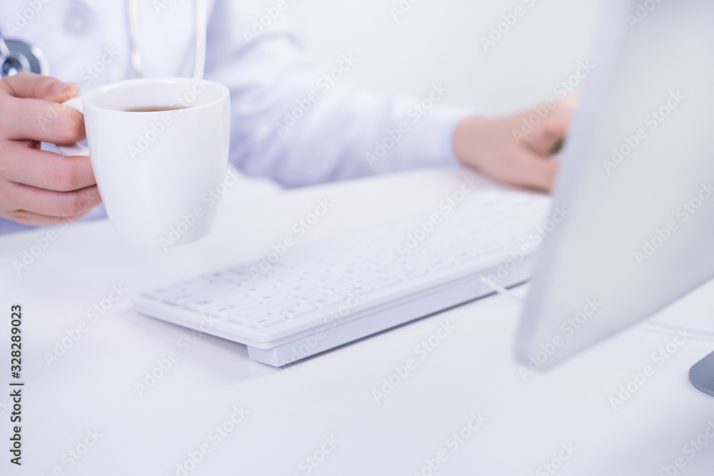 Business concept - Young female doctor woman working at office with computer, typing electronic medi