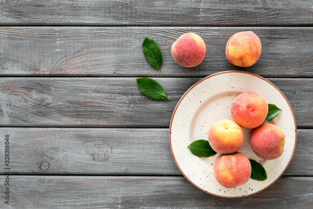 Summer fruits. Ripe red peaches on plate on dark wooden table top-down copy space