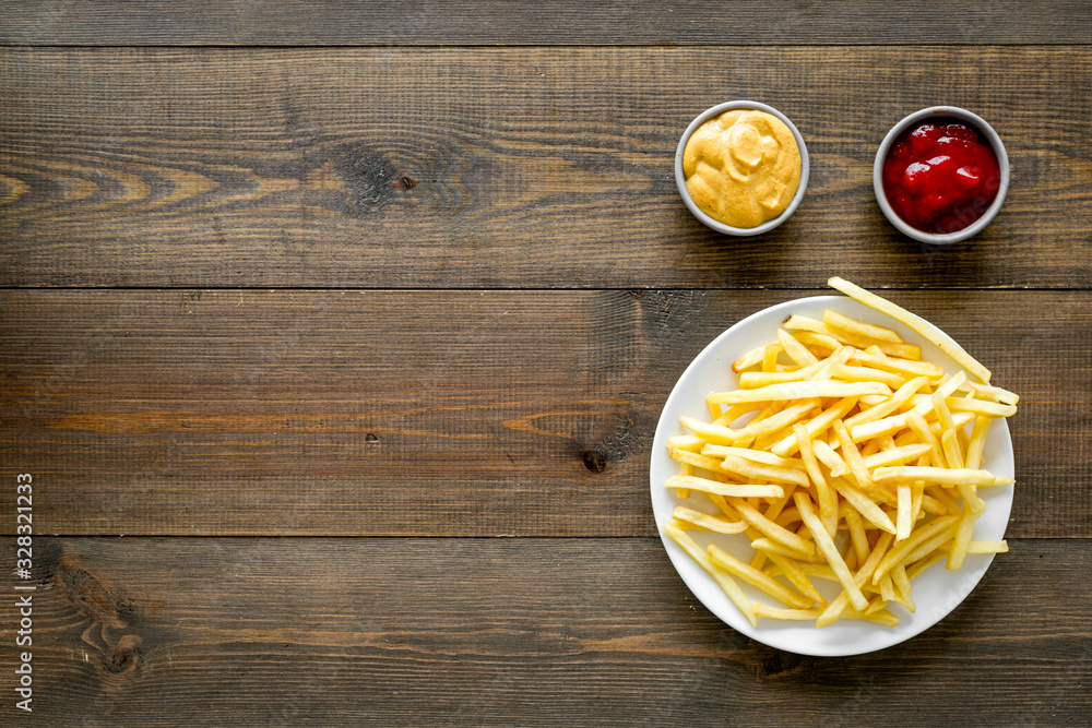 Fast food symbol. French fries on plate on dark wooden table top-down copy space