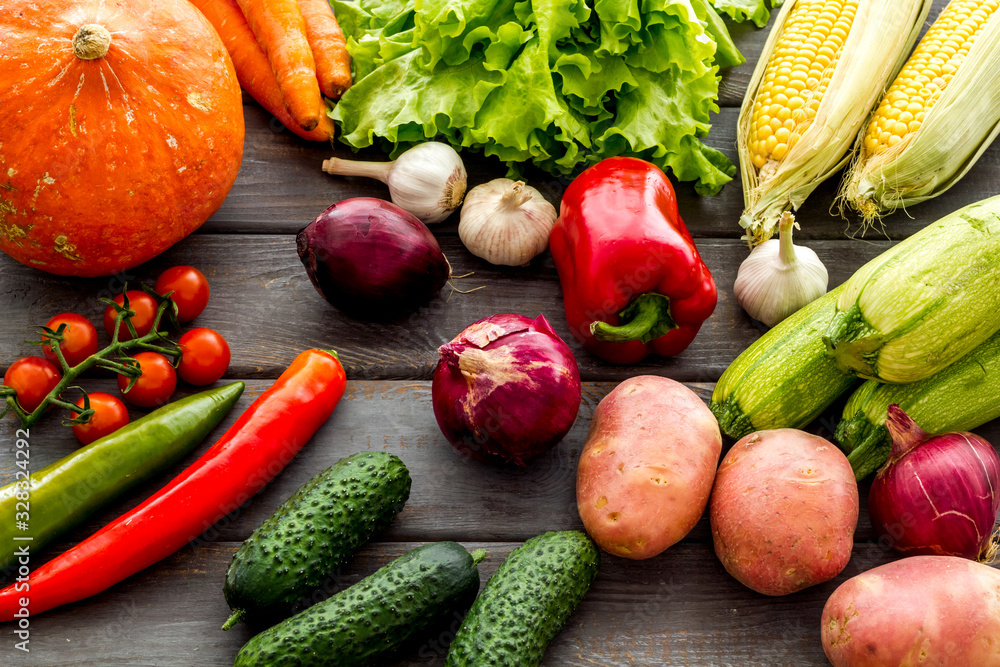 Fresh vegetables still life. Potato, cucumber, beet carrot, greenery on dark wooden background