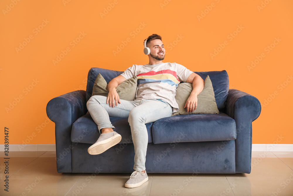 Young man listening to music while sitting on sofa at home