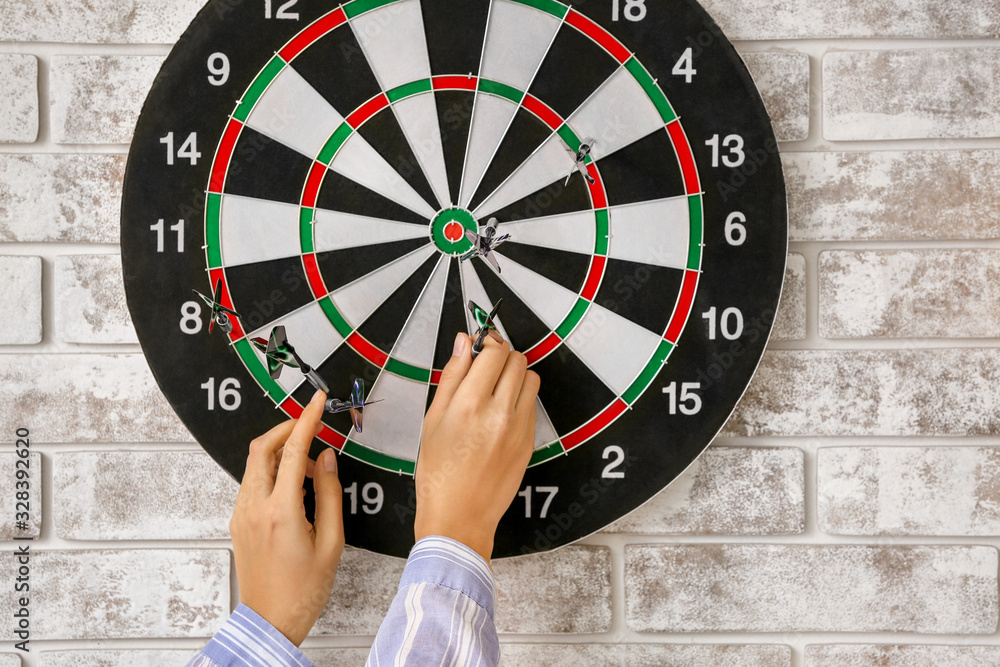 Young woman playing darts indoors