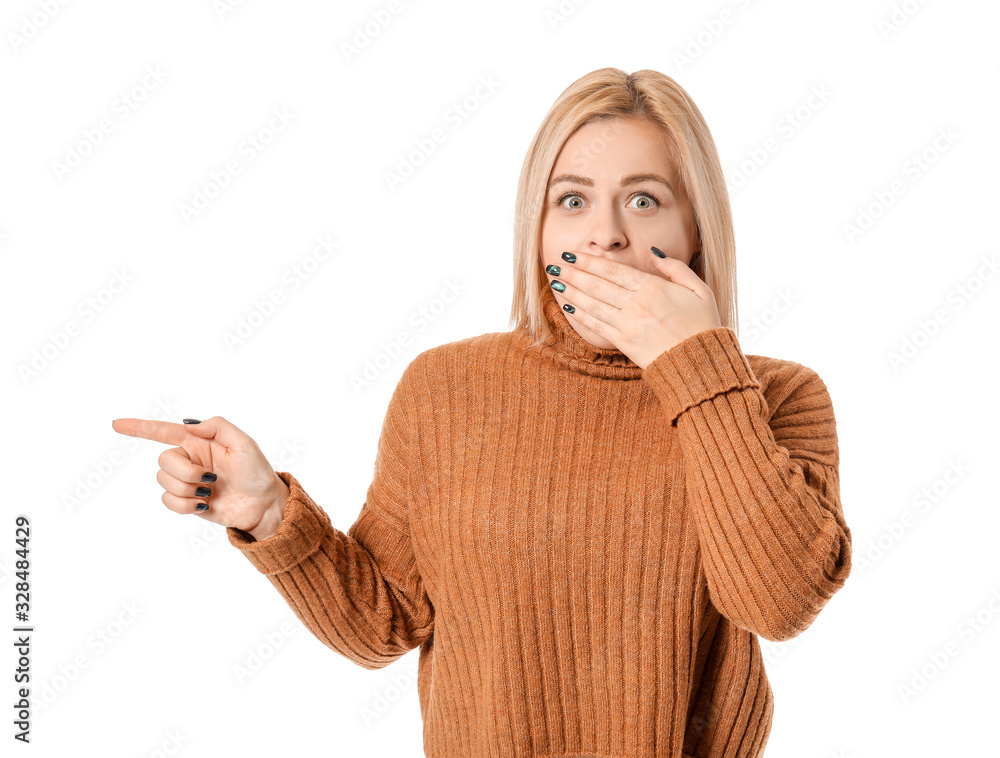 Shocked young woman pointing at something on white background