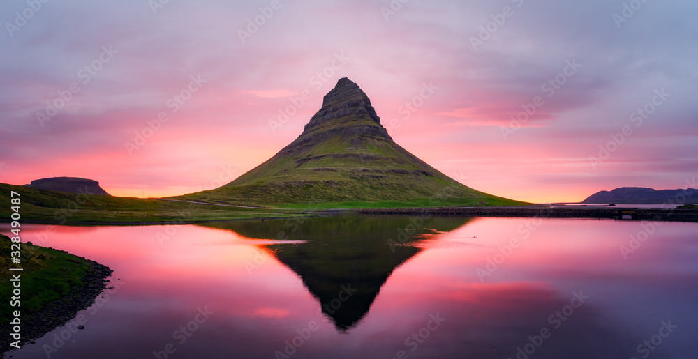 Picturesque panoramical landscape with Kirkjufell mountain, clear lake and cloudscape in sunset sky