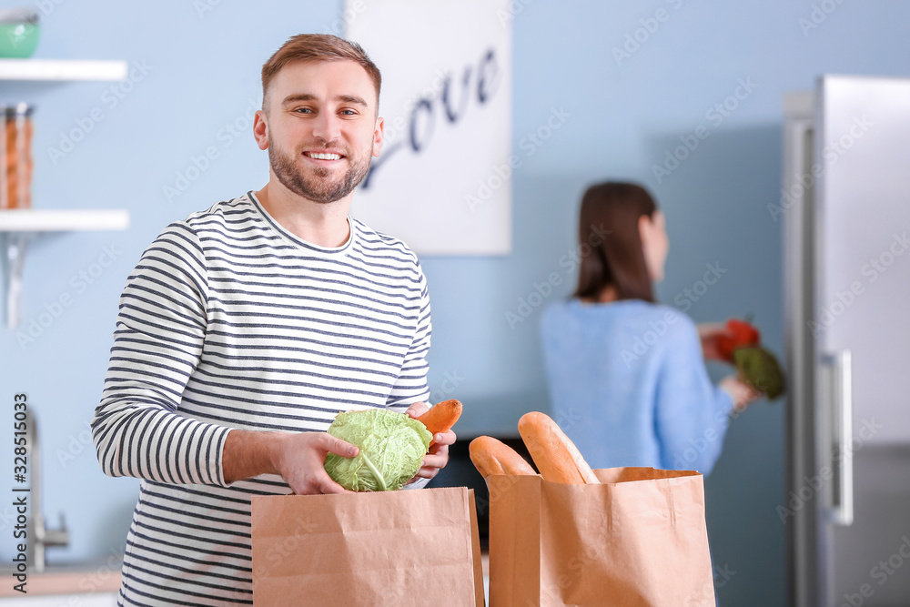 年轻夫妇在厨房里打开市场上的新鲜产品