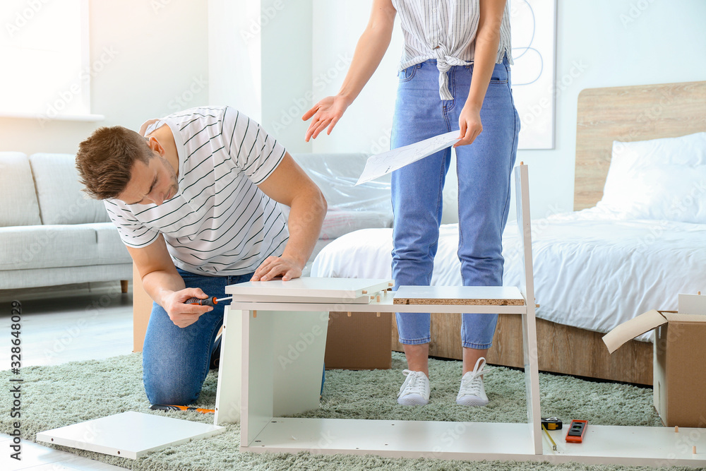 Young couple assembling furniture at home