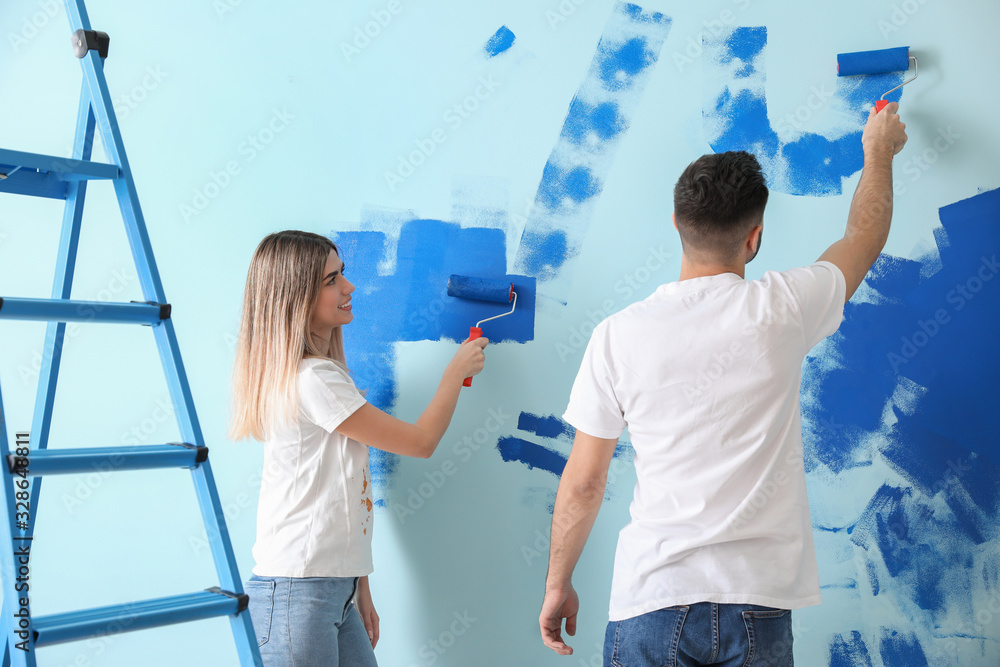 Happy young couple painting wall in their new house