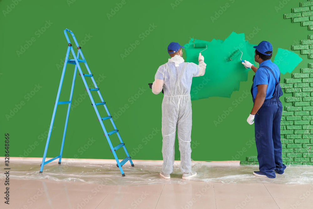 Male painters doing repair in room