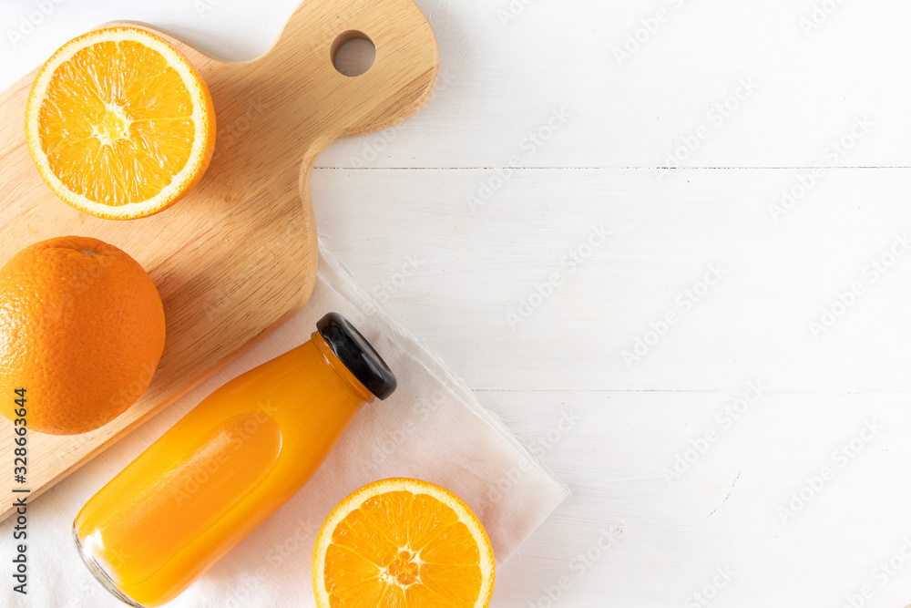 Orange juice in a glass bottle with sliced fruit on white wooden background, top view and flay lay o