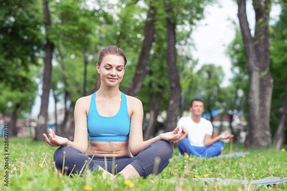 Girl meditates in lotus pose on green grass