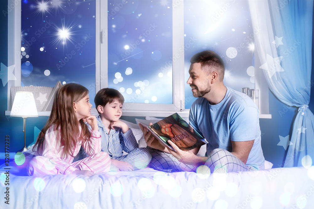 Father and his little children reading bedtime story at home