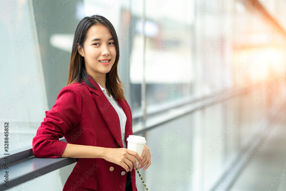 young office worker girl holding hot espresso paper cup leisurely walking on glass wall background t