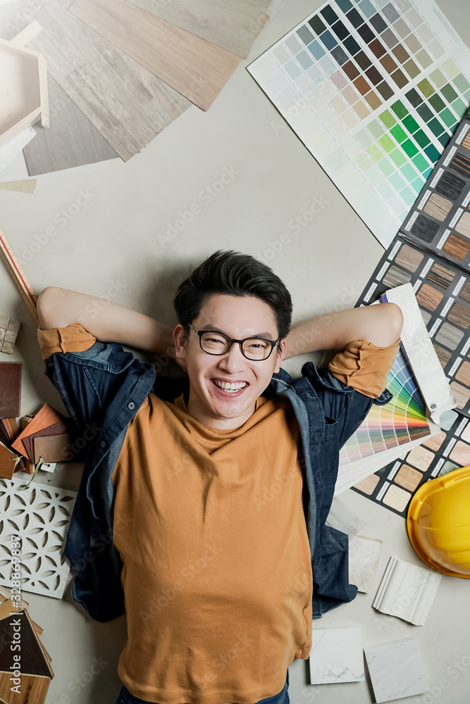 smart happiness asian man house owner laydown on floor with house material sample frame around home 