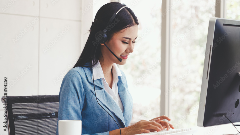 Customer support agent or call center with headset works on desktop computer while supporting the cu