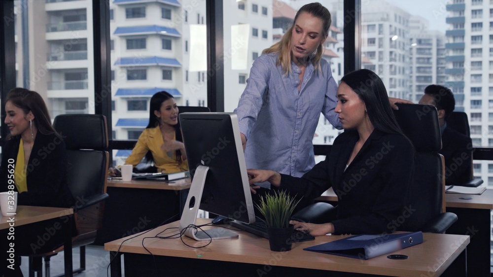 Young leader gives advice to young woman worker in modern office. Leadership and training concept.