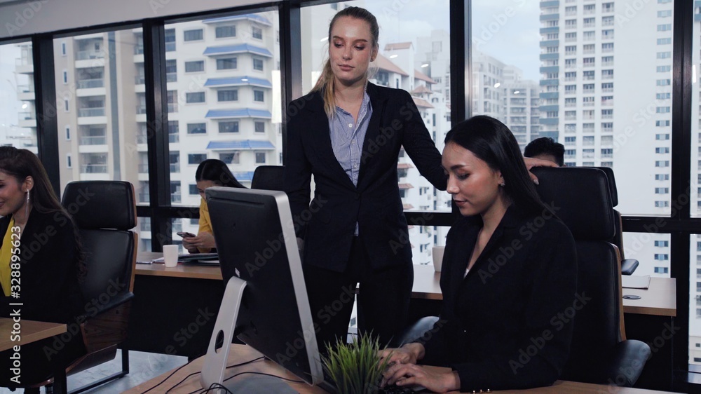 Young leader gives advice to young woman worker in modern office. Leadership and training concept.