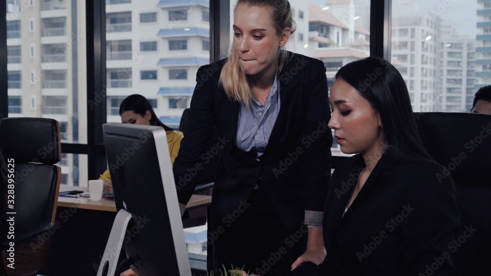 Young leader gives advice to young woman worker in modern office. Leadership and training concept.