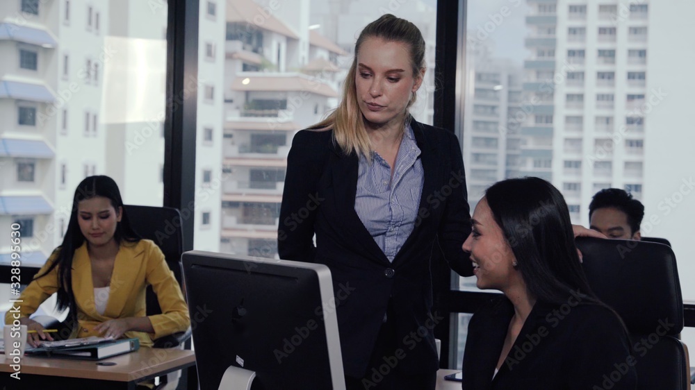 Young leader gives advice to young woman worker in modern office. Leadership and training concept.