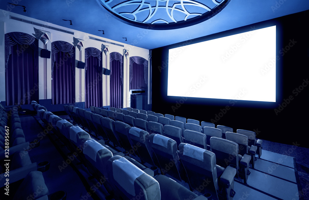 Cinema theater screen in front of seat rows in movie theater showing white screen projected from cin