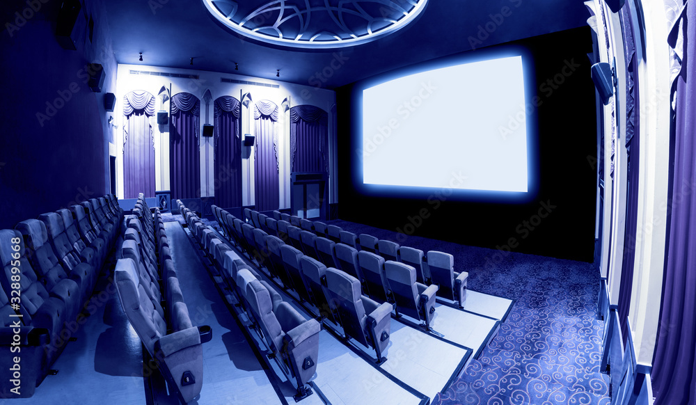 Cinema theater screen in front of seat rows in movie theater showing white screen projected from cin