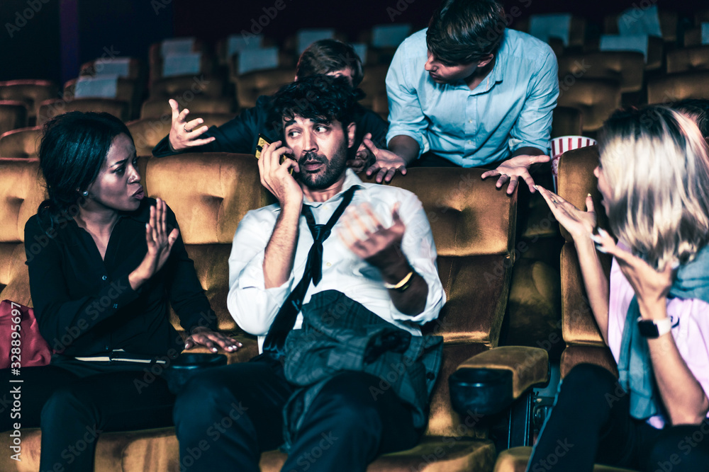 Annoying man talking on the mobile phone at the movie theater people in cinema is angry him