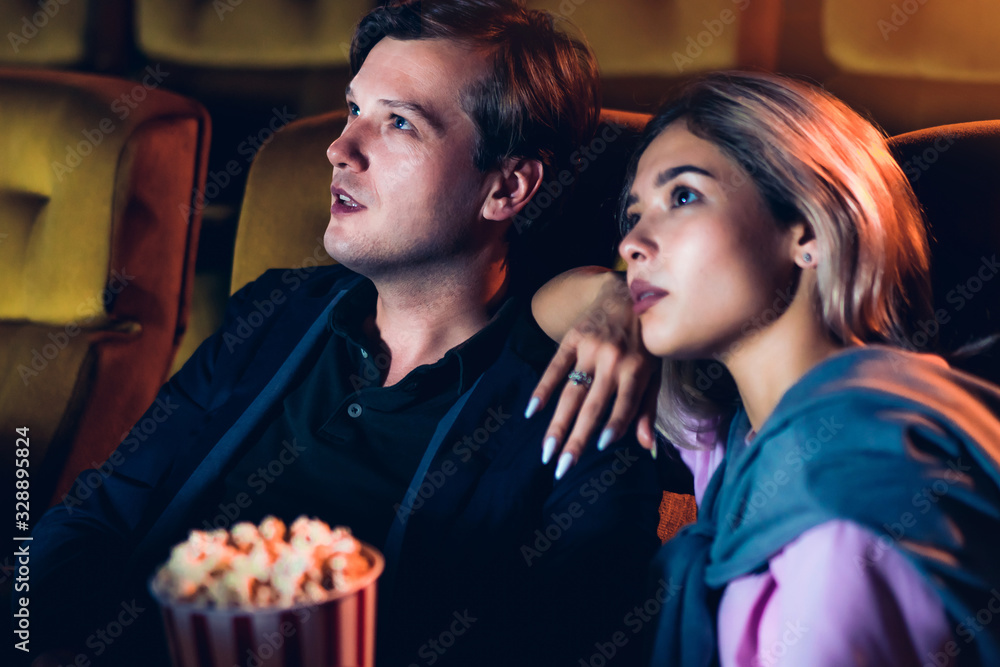 Caucasian lover enjoying to watch movie and eating popcorn together in the cinema