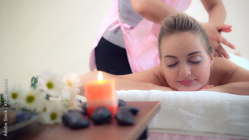 Relaxed woman getting back massage in luxury spa with professional massage therapist. Wellness, heal