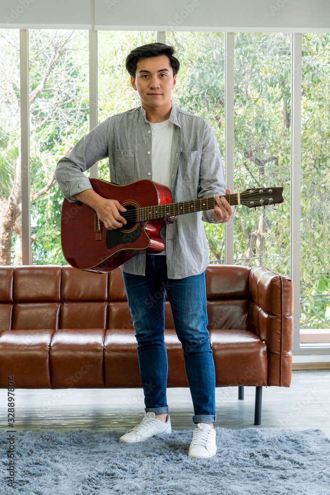 Young guitar player holding his guitar at home. Music and song concept.