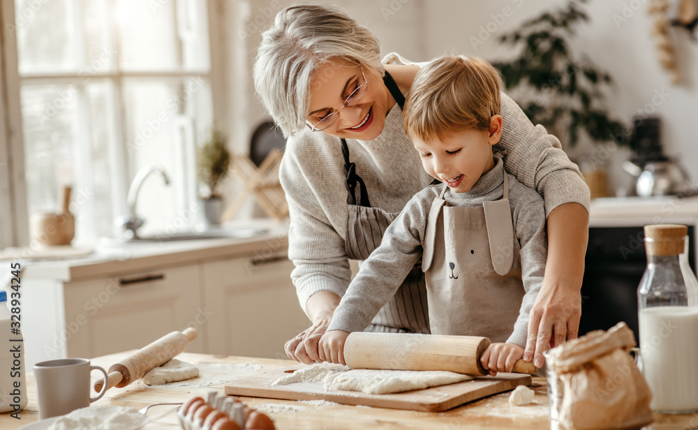 happy family grandmother and grandson child cook in kitchen, knead dough, bake cookies.