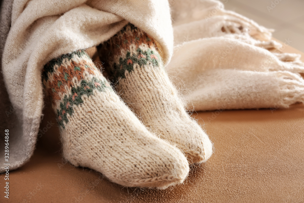 Legs of woman in knitted socks and plaid on color background