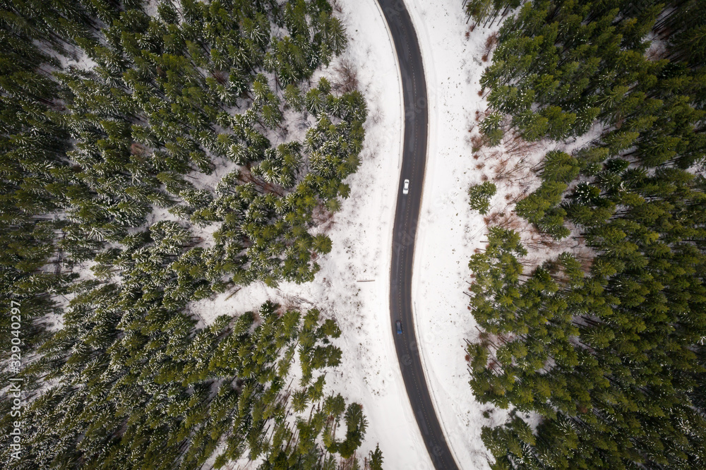 Flight over the winter mountains with road serpentine and snowy forest. Top down view. Landscape pho