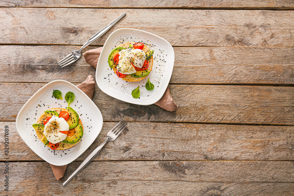 Sandwiches with poached eggs on wooden background