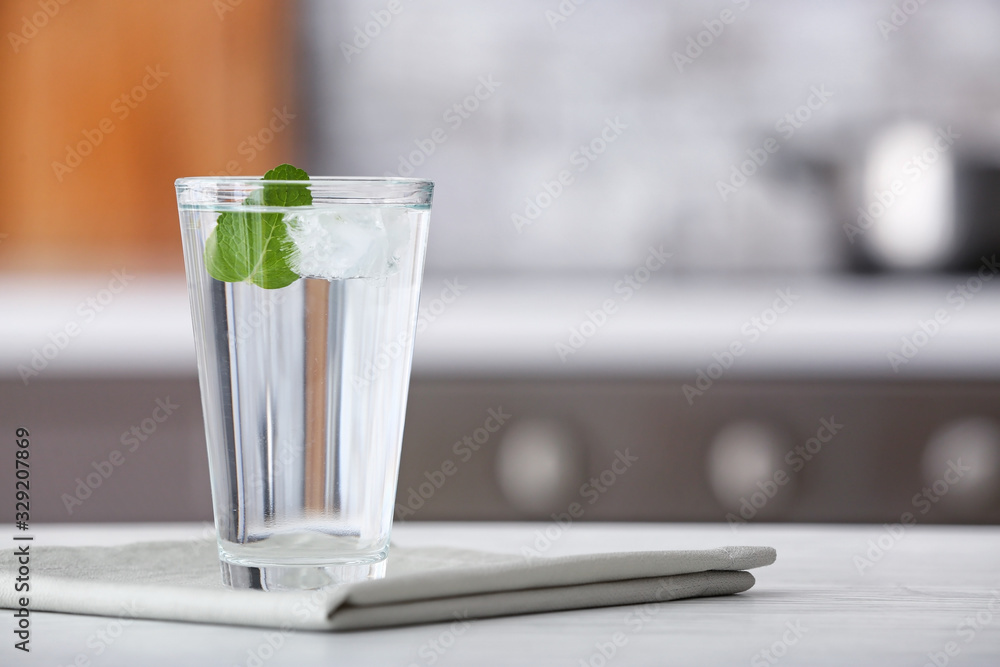 Glass of fresh cold water on table in kitchen