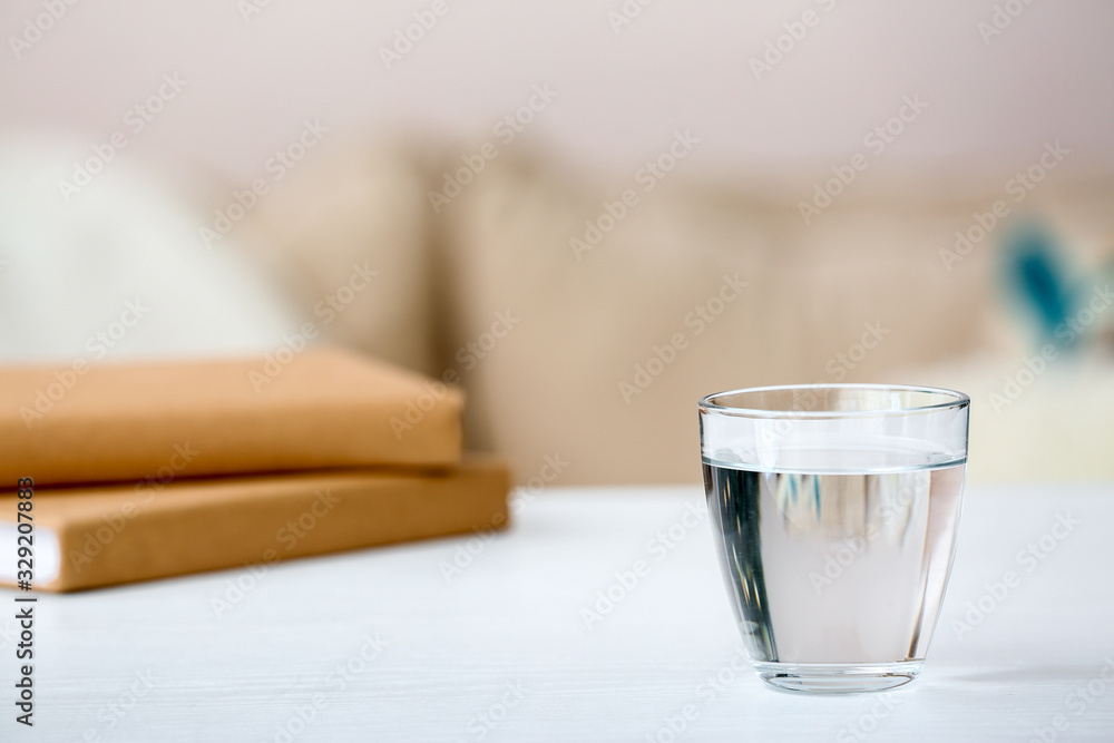 Glass of fresh cold water on table in room